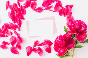 Mockup white greeting card, red petals and envelope with red peonies on a light  background