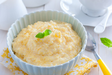 Milk corn porridge in a blue bowl, horizontal