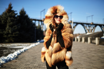 The girl walks through the city in a fur coat