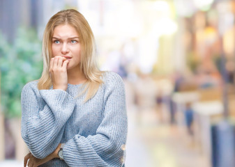 Young caucasian woman wearing winter sweater over isolated background looking stressed and nervous with hands on mouth biting nails. Anxiety problem.