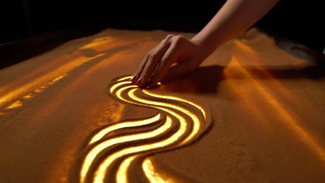 girl makes sand patterns on the table, sand animation