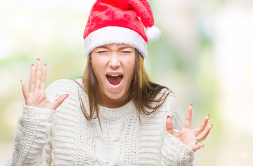 Young beautiful caucasian woman wearing christmas hat over isolated background celebrating mad and crazy for success with arms raised and closed eyes screaming excited. Winner concept