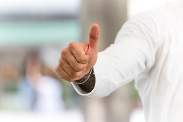 A man in white shirt is showing thumbs up sign in office with copy space