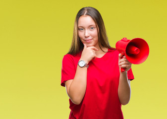 Young caucasian woman yelling through megaphone over isolated background serious face thinking about question, very confused idea