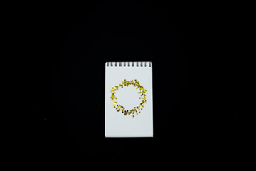 Spiral Notebook, realistic mockup White scetchbook on black abstract background with golden stars confetti.Horizontal top view..