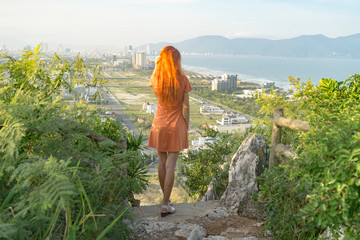 Travel girl with red hair is travelling in Marble Mountains ,staying on the top and watching a view...