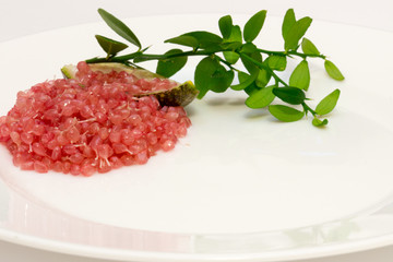 Delicious citrus caviar on a white plate decorated with a green sprig of citrus plants, Microcitrus australasica, Australian finger lime, close-up
