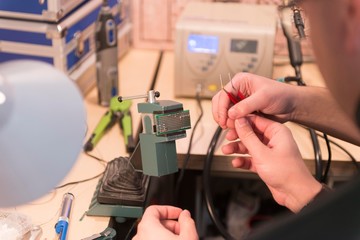 man soldering electronic board in workshop