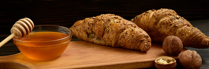 Fresh croissants with honey jar and nuts