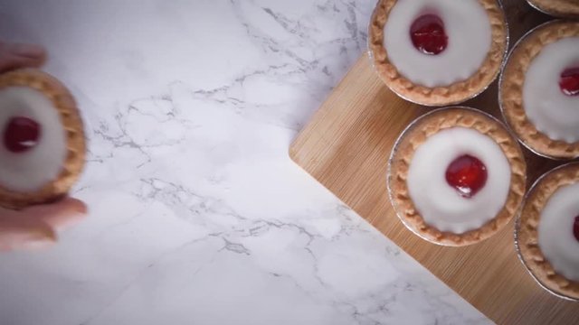 Bakewell Tarts flat lay top down against a marble background hand placing tart on wooden chopping board camera slide move studio shot