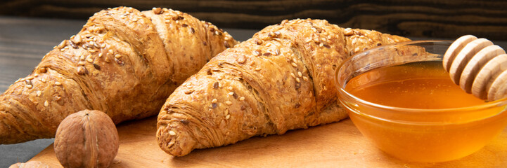 Fresh croissants with honey jar and nuts