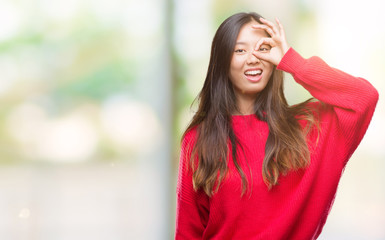 Obraz premium Young asian woman wearing winter sweater over isolated background doing ok gesture with hand smiling, eye looking through fingers with happy face.