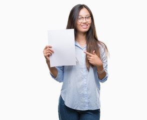 Fototapeta premium Young asian woman holding blank paper over isolated background very happy pointing with hand and finger