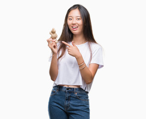 Young asian woman holding fresh organic over isolated background very happy pointing with hand and finger