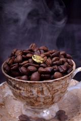 Fototapeta premium Golden coffee bean on freshly roasted ones in a cup against the dark background