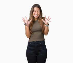 Obraz premium Young beautiful brunette woman over isolated background celebrating mad and crazy for success with arms raised and closed eyes screaming excited. Winner concept