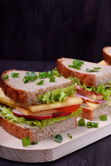 Sandwiches assortment on a wooden board against the dark background