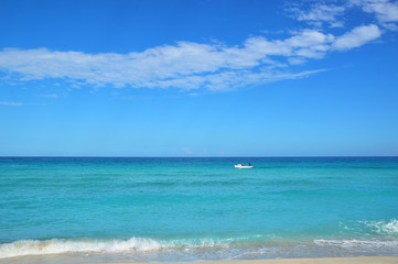coastline of the ocean, small waves, horizon, endless distance, white motor boat with silhouettes of people in the ocean
