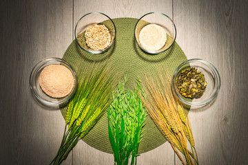 Mix of different kinds of flour in the bowls with fresh wheat and barley grains.