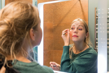 young attractive girl doing make-up before work