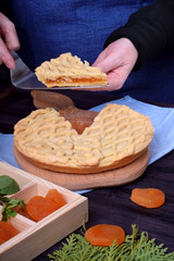 A piece of pie with dried apricots in female hands