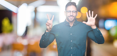 Young handsome business man wearing glasses over isolated background showing and pointing up with...