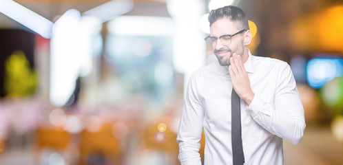 Young handsome business man wearing glasses over isolated background touching mouth with hand with painful expression because of toothache or dental illness on teeth. Dentist concept.