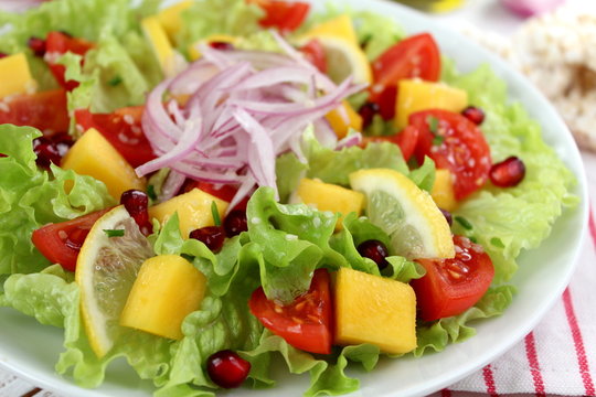 Fresh salad with lettuce, mango, tomato, onion, sesame and pomegranate. Diet food. Top view. Vegetarian and vegan food.