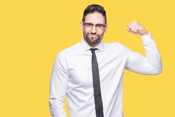 Young handsome business man wearing glasses over isolated background Strong person showing arm muscle, confident and proud of power