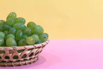 green grape in a bowl on colored background