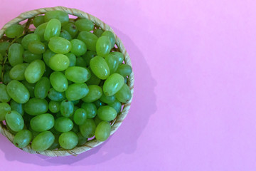 green grape in a bowl on colored background