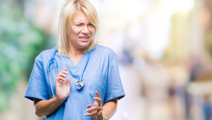 Young beautiful blonde doctor woman wearing medical uniform over isolated background disgusted...