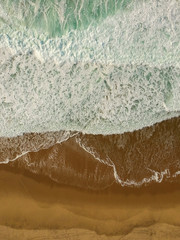 Aerial view of sandy beach with waves and clear ocean water. Drone photo 