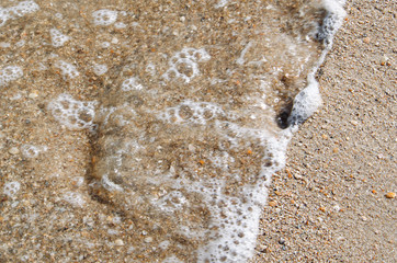 Sea foam in blur on the sandy shore
