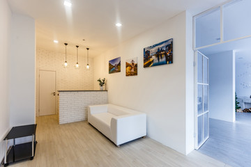 Stool with vase on carpet in bright living room with white sofa and plants
