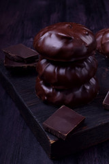 Zephyr covered with chocolate against the dark background. Dark photo