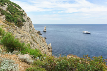 Fototapeta na wymiar Rocky steep coast of the Black sea and a sailing ship. Rock Sail near Cape Limen-Burun