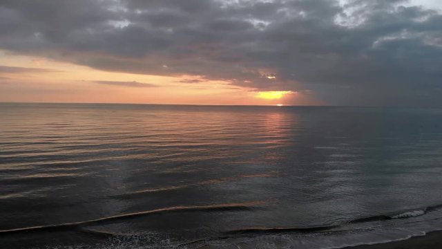 Dark sunset above ocean before storm a calm water surface with sunbeams reflections between nimbostratus clouds and dramatic light