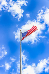 American flag against a blue sky with white clouds