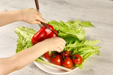 The child cuts vegetables with a knife