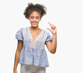 Young afro american woman over isolated background smiling and confident gesturing with hand doing size sign with fingers while looking and the camera. Measure concept.