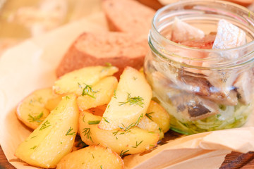Plate of pieces of herring with fried potato,onion. Close up with selective focus.