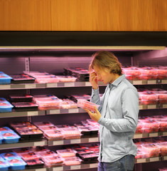 Teenager  purchasing a packet of meat at the supermarket
