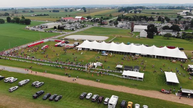 High angle aerial, crowds walk around fairgrounds and prepare for 5k race.