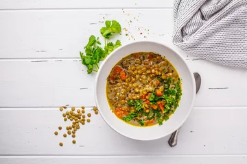 Poster Homemade vegan lentil soup with vegetables and cilantro, white wooden background. © vaaseenaa