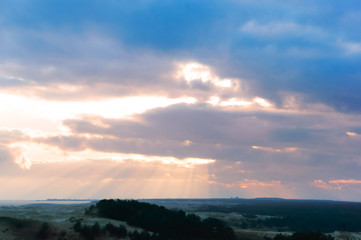 Sunset over sand dune. Sunset over the sea. Red and yellow sky in the rays of the sunset.