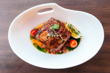 Top view of Baked juicy chicken breast and crispy skin with tomato and lemon served with white wine.