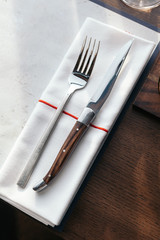 Knife and fork with napkin on wooden table for fine dining. Luxury cutlery set.