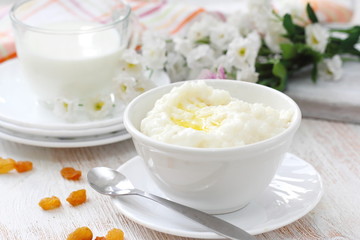 Obraz na płótnie Canvas Sweet rice porridge with butter and mug of milk