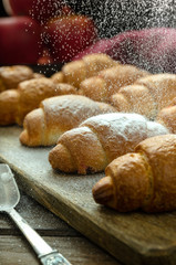 Croissants on a wooden stand sprinkle with powdered sugar.